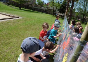 Dzieci w ogrodze, skupione torzą wiosenny obraz na folii, widom z boku